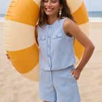 Model draagt de blauwe Amanda co-ord set van Ydence op het strand, zomerse outfit met mouwloos gilet en bijpassende short.