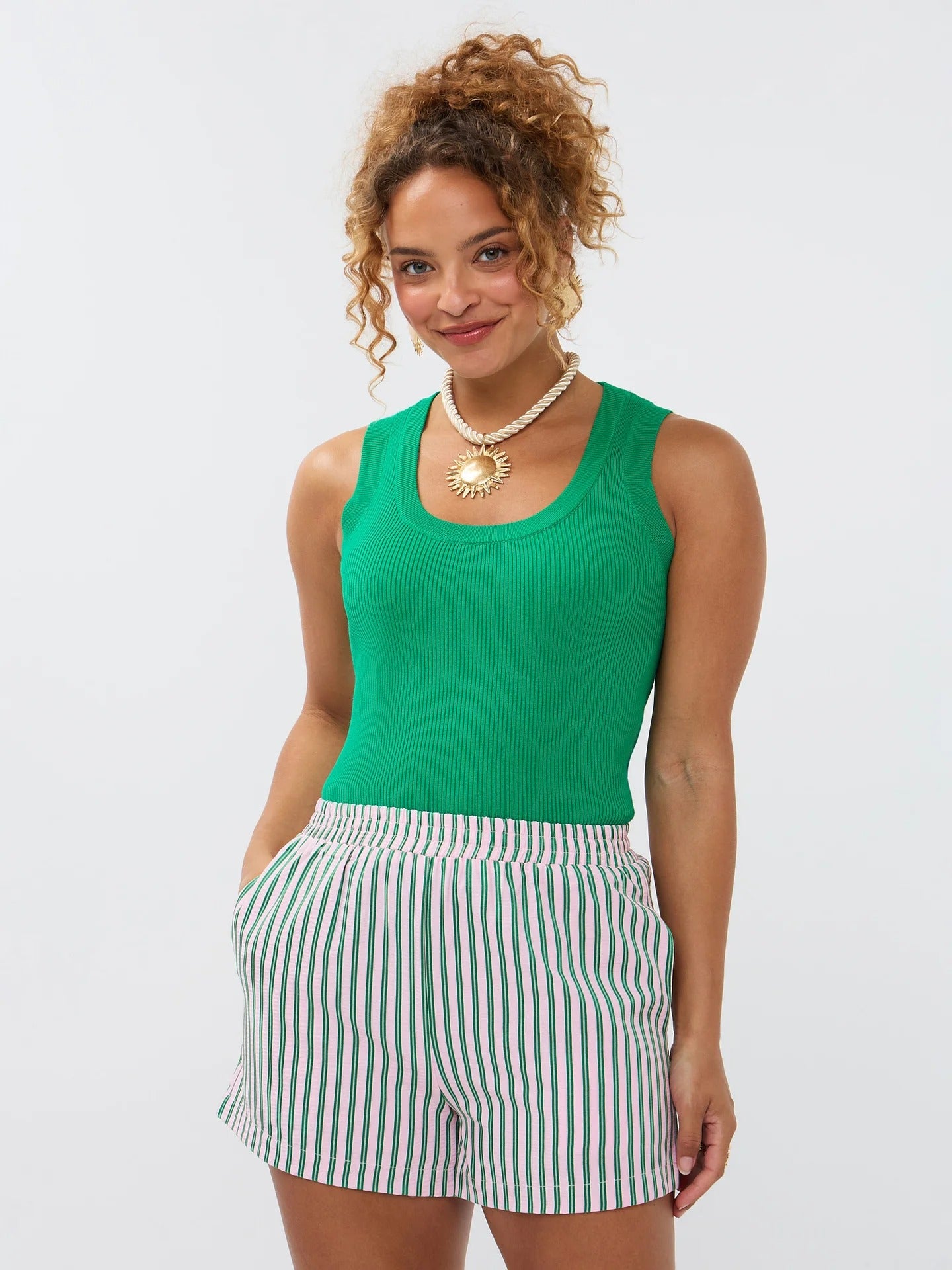 Model draagt de Ydence short Belle, een zomerse short met roze en groene verticale strepen en elastische tailleband.
