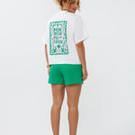 Model draagt het Ydence T-shirt More Amore met opvallende rugprint in roze en groen met de tekst 'More Amore Por Favor'.