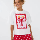 Model draagt het Ydence T-shirt met lobster print, gecombineerd met een rode short met witte bloemetjes.