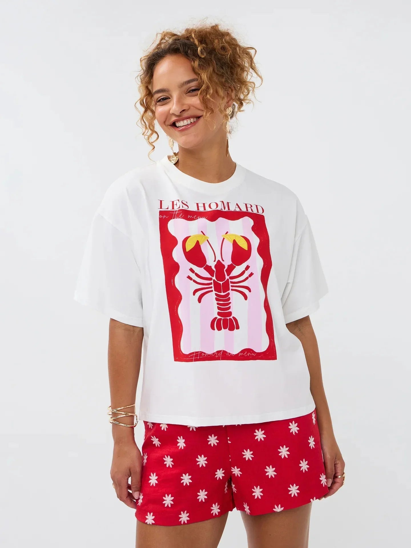 Model draagt het Ydence T-shirt met lobster print, gecombineerd met een rode short met witte bloemetjes.