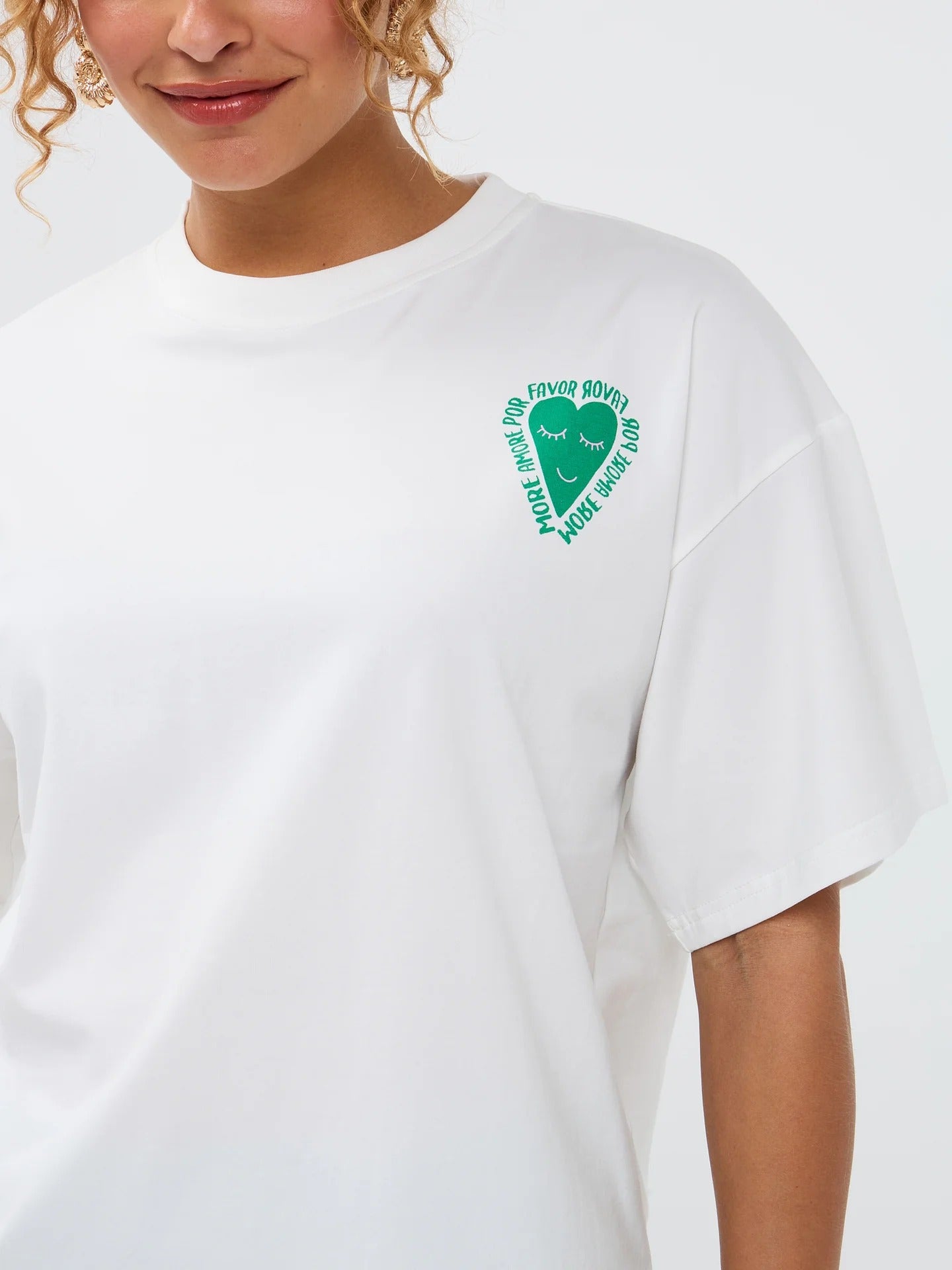 Model draagt het casual Ydence T-shirt More Amore met kleurrijke backprint en groene short met witte streepjes.
