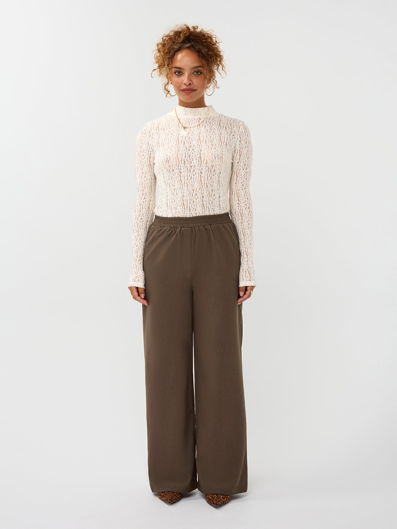 Model draagt de ydence yade pants in de kleur mud met een witte top.