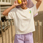 Model draagt de Mima short met een wit T-shirt op het strand, onderdeel van de Mima & Arlette co-ord set.