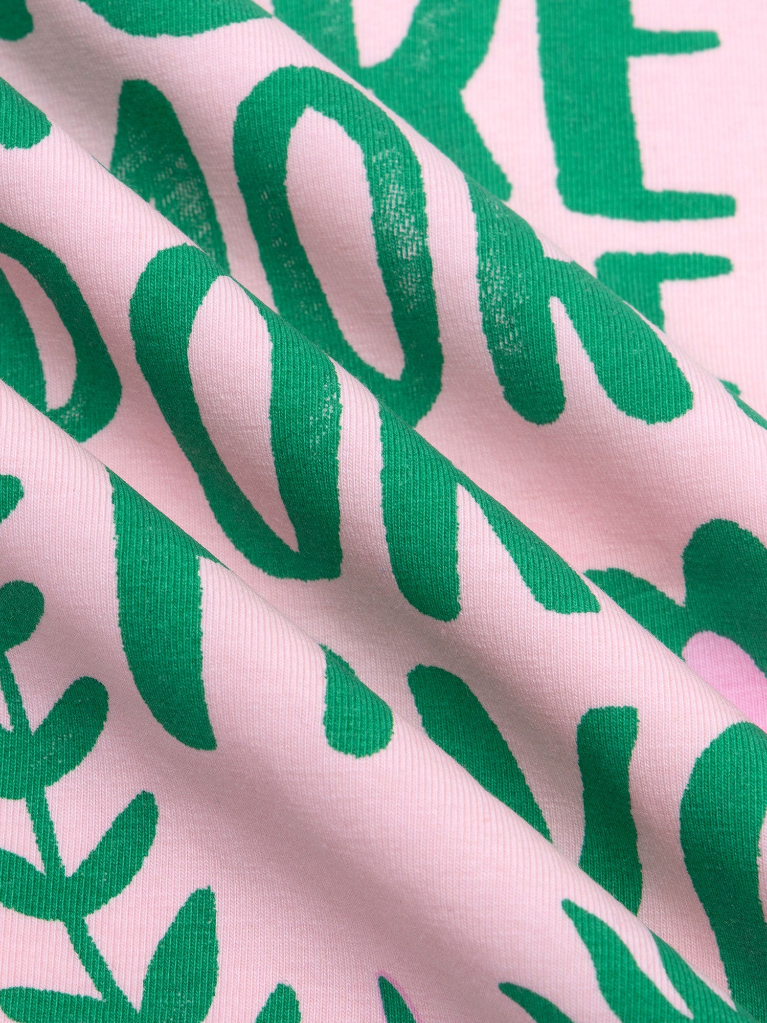 Detailopname van de roze en groene print op het T-shirt.