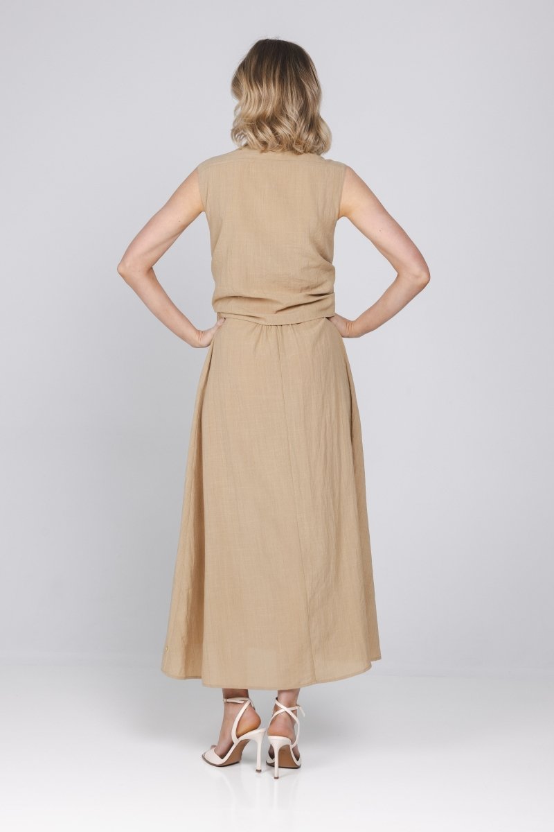 Een vrouw, van achteren gefotografeerd, draagt een mouwloze, zandkleurige midi-jurk | Accentil Diva Dress Sand | Jo&Co Club
