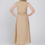 Een vrouw, van achteren gefotografeerd, draagt een mouwloze, zandkleurige midi-jurk | Accentil Diva Dress Sand | Jo&Co Club