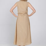 Een vrouw, van achteren gefotografeerd, draagt een mouwloze, zandkleurige midi-jurk | Accentil Diva Dress Sand | Jo&Co Club