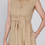 Een close-up van een model dat een mouwloze, zandkleurige jurk draagt | Accentil Diva Dress Sand | Jo&Co Club