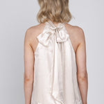 Een vrouw, van achteren gefotografeerd, draagt een mouwloze haltertop van een | Accentil Flore Top Satin Pink | Jo&Co Club