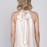 Een vrouw, van achteren gefotografeerd, draagt een mouwloze haltertop van een | Accentil Flore Top Satin Pink | Jo&Co Club