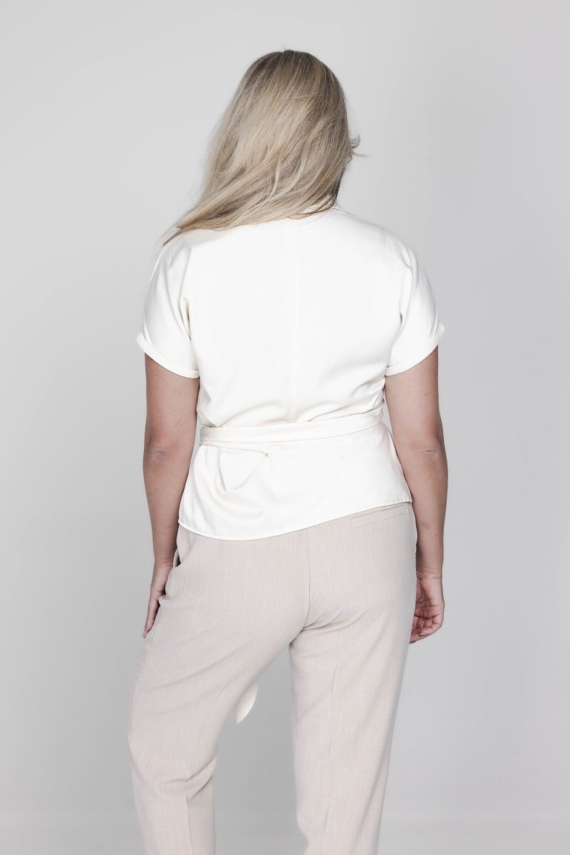 Een model, van achteren gefotografeerd, draagt een off-white blouse met | Accentil Jasmin Blouse Off White | Jo&Co Club