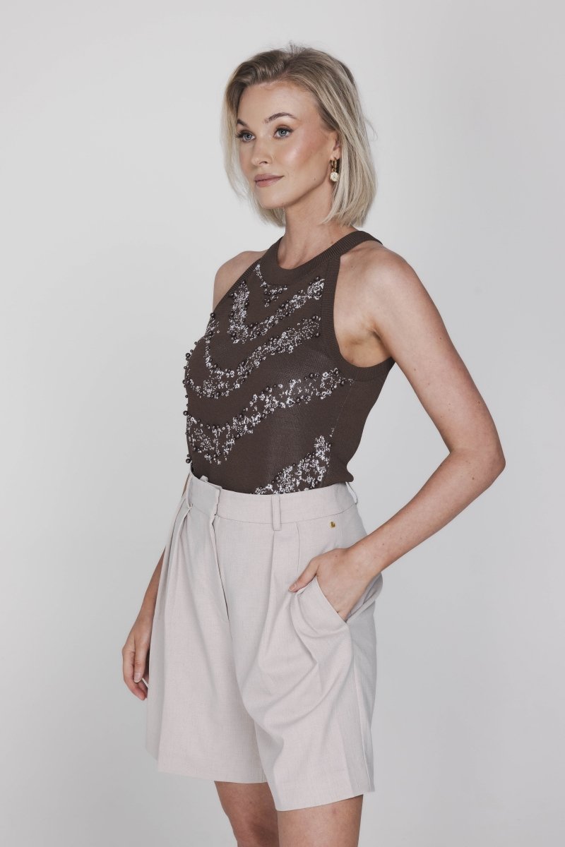 Een model met een korte blonde bob wordt in een driekwart pose getoond tegen een | Accentil Jolie Top Espresso | Jo&Co Club