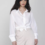 Een model met lang, donker haar poseert in een witte wikkelblouse en een | Accentil Kira Blouse Off White | Jo&Co Club