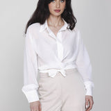 Een model met lang, donker haar poseert in een witte wikkelblouse en een | Accentil Kira Blouse Off White | Jo&Co Club