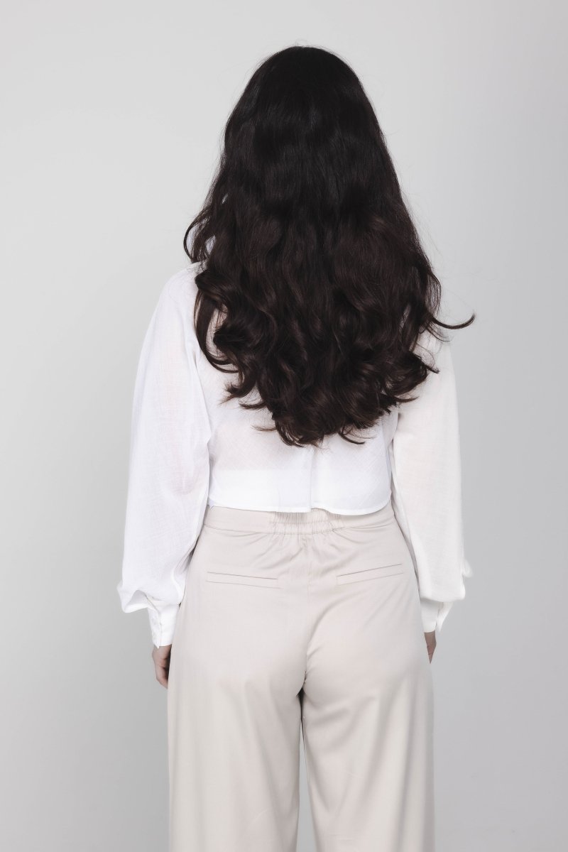 Een model, van achteren gefotografeerd, draagt een cropped witte blouse met | Accentil Kira Blouse Off White | Jo&Co Club