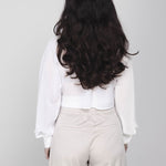 Een model, van achteren gefotografeerd, draagt een cropped witte blouse met | Accentil Kira Blouse Off White | Jo&Co Club