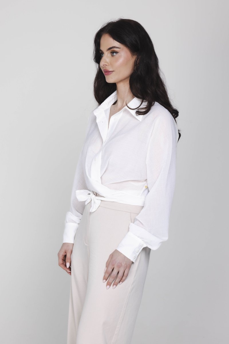 Een model, gepositioneerd in een driekwart aanzicht, draagt een gebroken witte | Accentil Kira Blouse Off White | Jo&Co Club