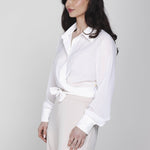 Een model, gepositioneerd in een driekwart aanzicht, draagt een gebroken witte | Accentil Kira Blouse Off White | Jo&Co Club