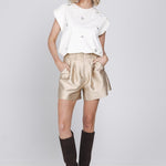Een model toont een zandkleurige, glinsterende short met hoge taille en plooien | Accentil Lore Short Sand | Jo&Co Club