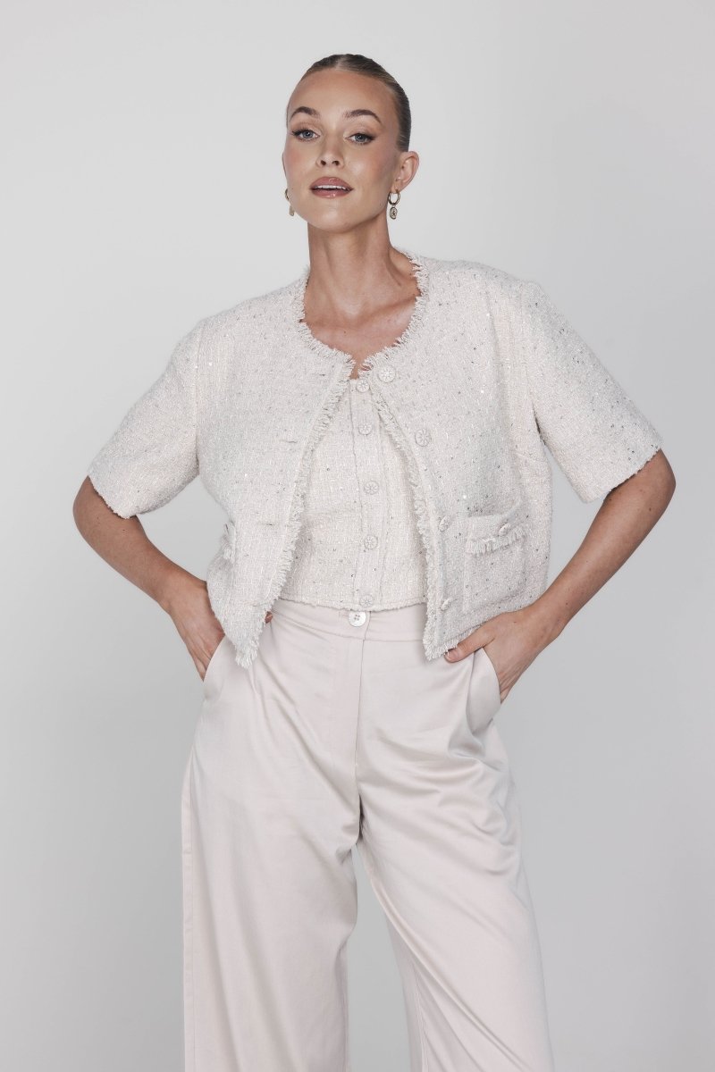 Een model poseert in een chique, gecoördineerde outfit tegen een lichte, egale | Accentil May Top Dolce Beige | Jo&Co Club