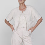 Een model poseert in een chique, gecoördineerde outfit tegen een lichte, egale | Accentil May Top Dolce Beige | Jo&Co Club