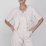 Een model poseert in een chique, gecoördineerde outfit tegen een lichte, egale | Accentil May Top Dolce Beige | Jo&Co Club