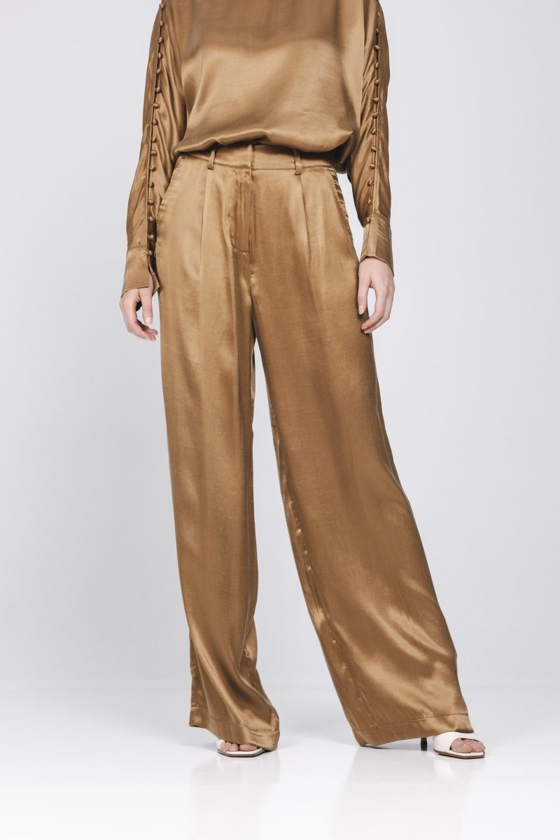 Een model, gefotografeerd vanaf de borst, draagt een complete set in een glanzende | Accentil Mira Pants Mokka | Jo&Co Club