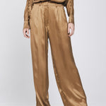 Een model, gefotografeerd vanaf de borst, draagt een complete set in een glanzende | Accentil Mira Pants Mokka | Jo&Co Club