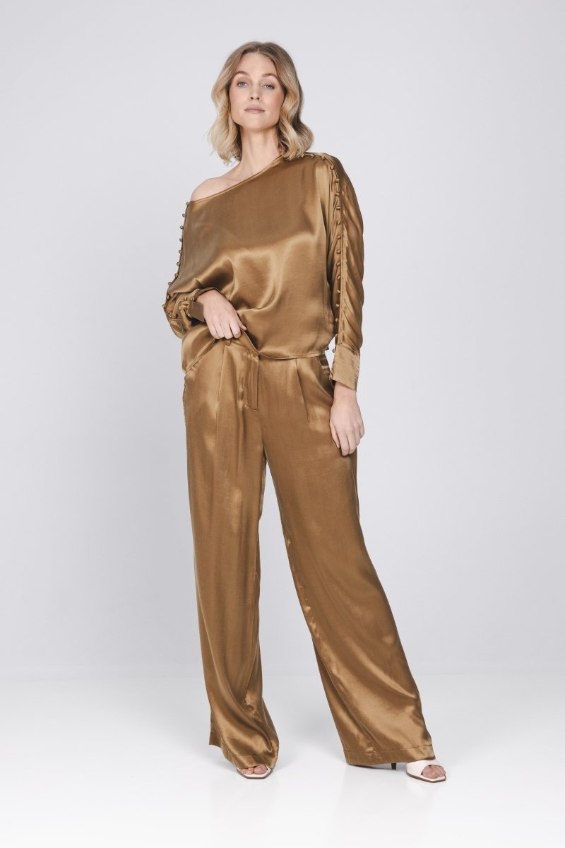 Een model toont een complete look, bestaande uit een glanzende, mokkakleurige top | Accentil Mira Pants Mokka | Jo&Co Club
