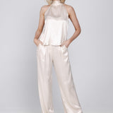 Een model poseert in een elegante, tweedelige set tegen een lichte, egale | Accentil Mira Pants Satin Pink | Jo&Co Club
