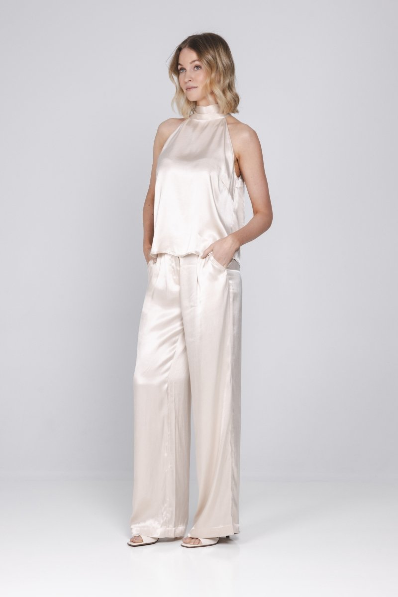 Een model met blond, golvend haar poseert in een tweedelige satijnen set tegen | Accentil Mira Pants Satin Pink | Jo&Co Club