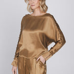 Een model met blond, golvend haar poseert tegen een lichtgrijze achtergrond | Accentil Moda Blouse Mokka | Jo&Co Club
