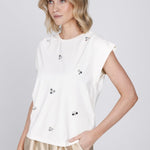 Een model met blond, golvend haar tot op de schouders draagt een gebroken witte top | Accentil Nivi Top White | Jo&Co Club