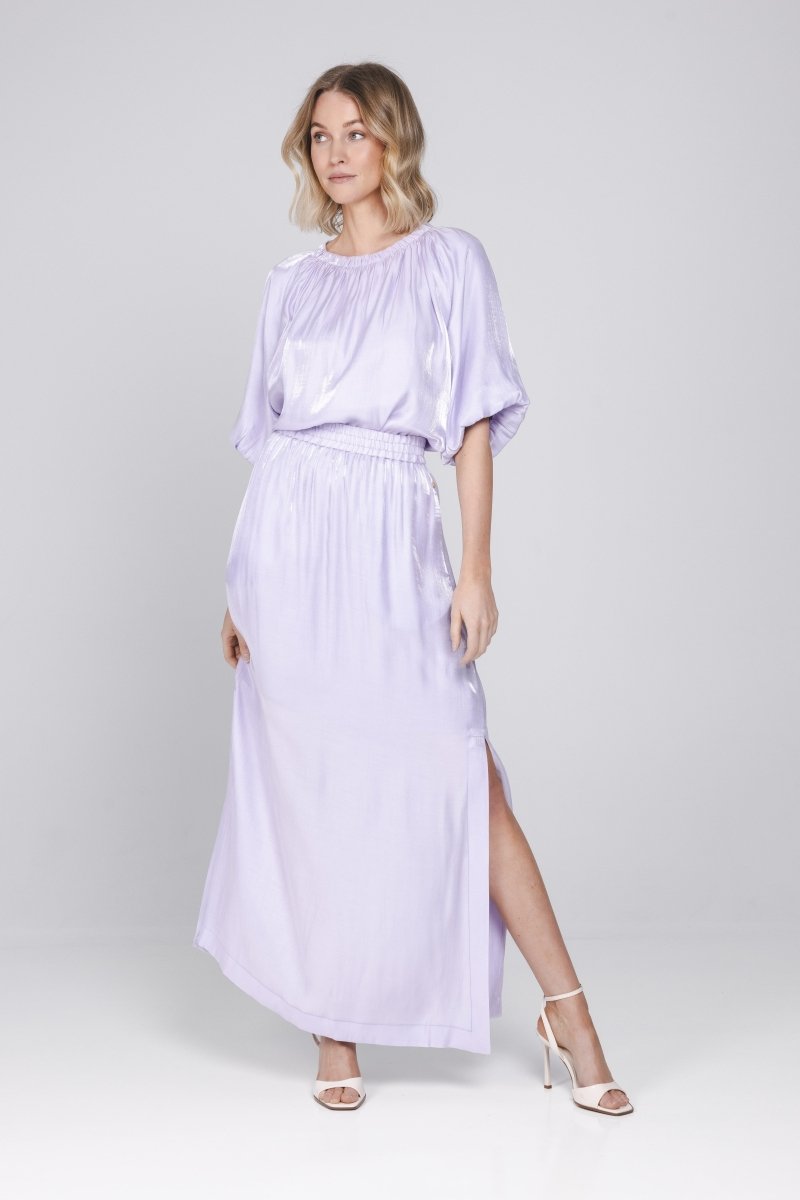 Een studiomodel toont een lila set, bestaande uit een blouse en bijpassende rok | Accentil Sere Blouse Lila | Jo&Co Club