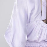 Detailopname van de achterkant van een model dat een glanzende lila blouse draagt | Accentil Sere Blouse Lila | Jo&Co Club