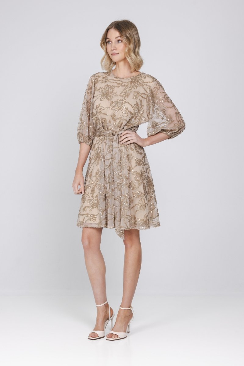 Een model wordt volledig in beeld gebracht tegen een lichtgrijze achtergrond | Accentil Vive Dress Sand | Jo&Co Club