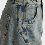 Detailopname van de vintage wassing en de werkzak op de dij van de barrel jeans | Jo&Co Club