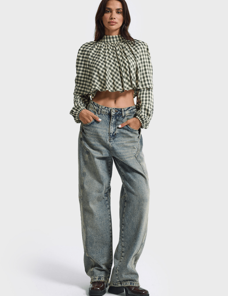 Model draagt de lichtblauwe barrel jeans met een geruite blouse | Jo&Co Club