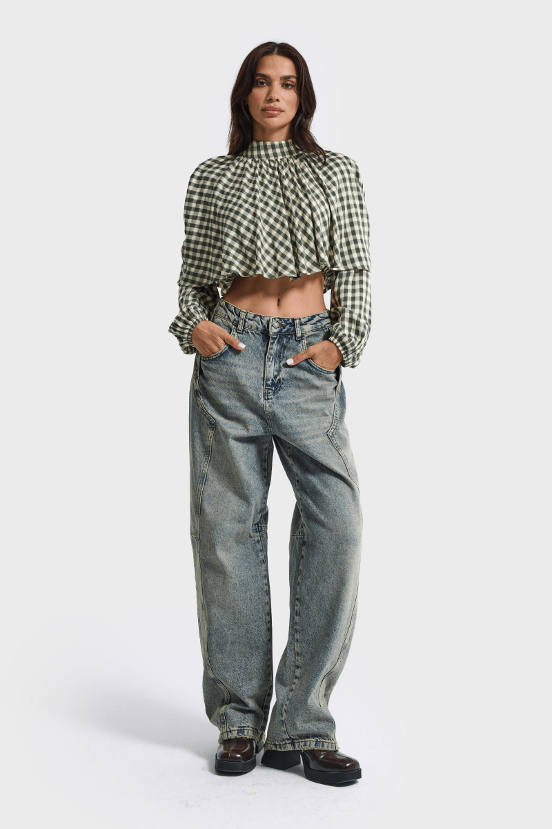 Model draagt de lichtblauwe barrel jeans met een geruite blouse | Jo&Co Club