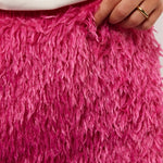 Close-up van de fluffy textuur van de roze Arianne rok van Fluresk, met hand die licht de stof vasthoudt voor detailweergave.