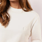 Detail van het witte Fluresk Brix T-shirt met ton-sur-ton geborduurd logo op de borst en subtiele ronde hals.