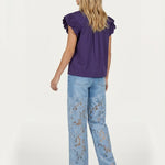 Achterkant van outfit: paarse top met ruches en lichtblauwe jeans met kanten bloemen. | Jo&Co Club