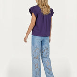 Achterkant van outfit: paarse top met ruches en lichtblauwe jeans met kanten bloemen. | Jo&Co Club