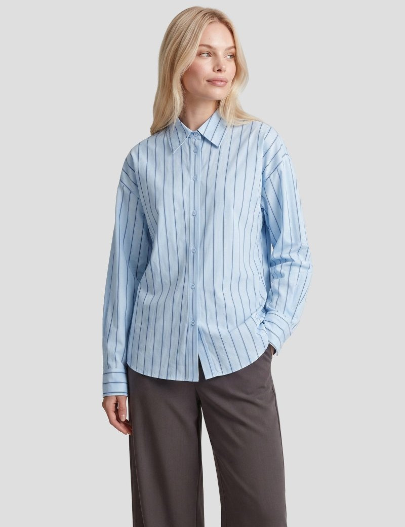 Gestreepte blouse Fluresk Joan in lichtblauw – oversized, op een grijze wijde pantalon | Jo&Co Club