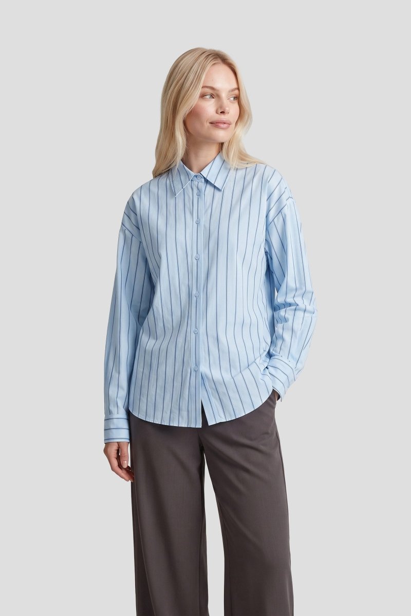 Gestreepte blouse Fluresk Joan in lichtblauw – oversized, op een grijze wijde pantalon | Jo&Co Club