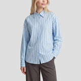 Gestreepte blouse Fluresk Joan in lichtblauw – oversized, op een grijze wijde pantalon | Jo&Co Club