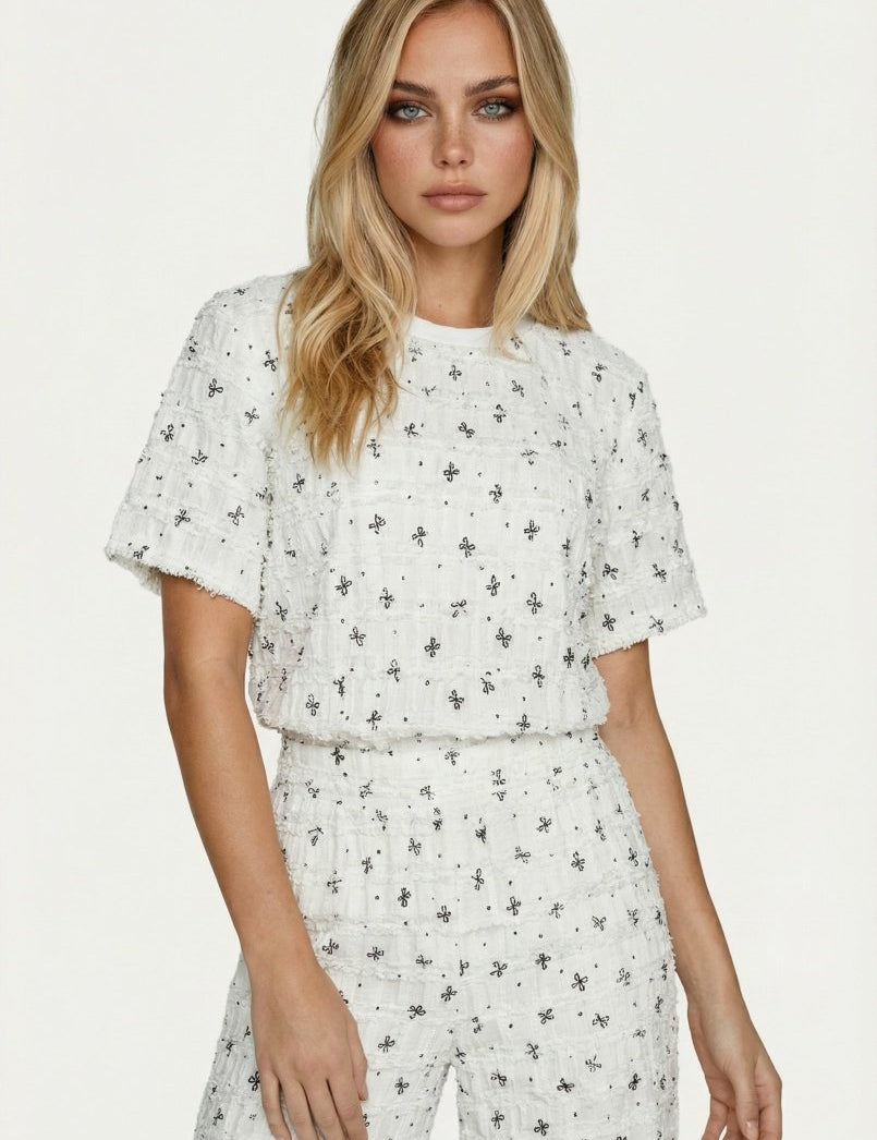 Witte T-shirt met zwart geborduurd patroon en textuur, gedragen door een model | Jo&Co Club