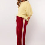 Zijaanzicht van de rode Fluresk Jorina pants met contrasterende strepen langs de pijp.