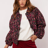 Model draagt het Fluresk Mirabel Jacket open over een witte sweater en bordeauxrode broek.